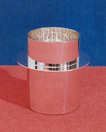 Silver-colored, hat-shaped container against a blue and pink background. The container is cylindrical with a wide, flat brim.