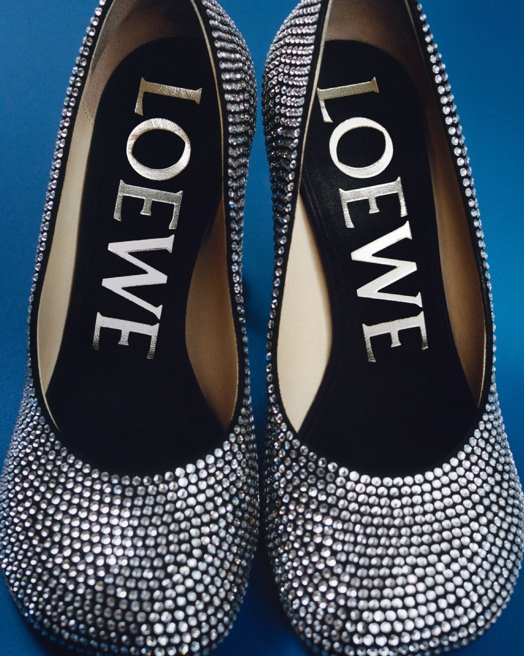 Elegant pair of silver Loewe high heels, showcasing luxury fashion footwear with shimmering embellishments and the brand logo.