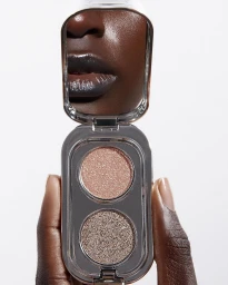 Close-up of a person holding an open compact makeup palette reflecting lips, photographed by Jeanne Lucas in Paris.
