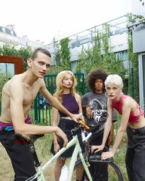 Group of four young models posing outdoors in Paris around a light-coloured bicycle shot by Jeanne Lucas.