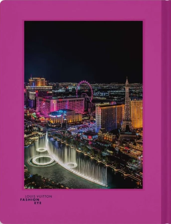 Nighttime aerial view of Las Vegas Strip featuring the Bellagio fountains, hotels, and the Eiffel Tower replica with a magenta frame.