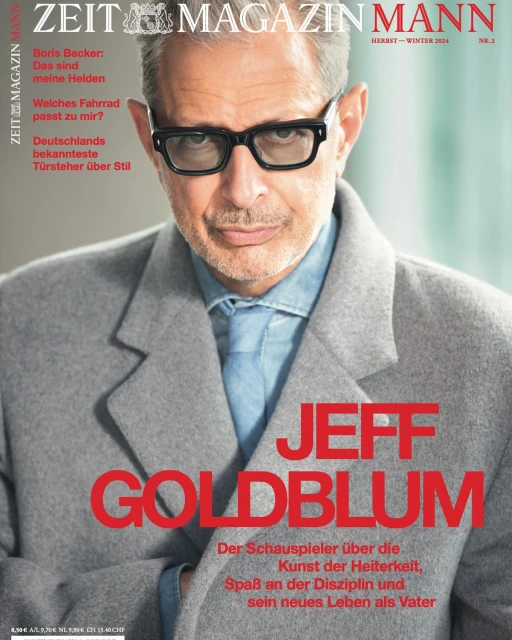 Magazine cover featuring Jeff Goldblum in a grey coat and black glasses, promoting an article on acting and life as a father.