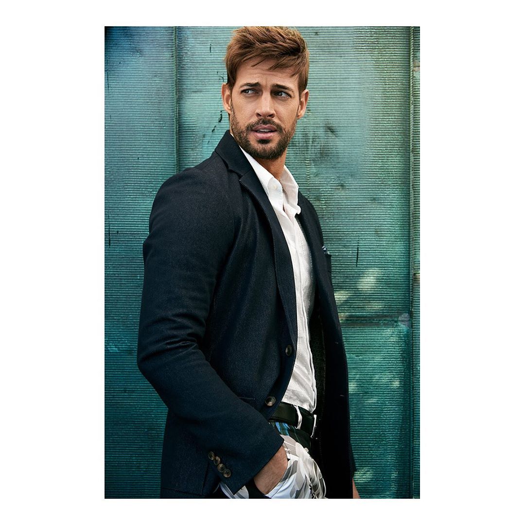 Portrait of a light-skinned adult male with auburn hair wearing a blue blazer and white shirt, looking off-camera in a photo studio.