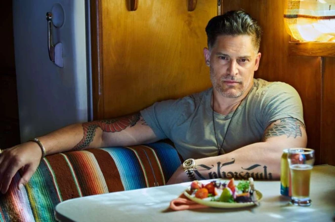 Portrait of actor Joe Manganiello with tattoos seated at a table in a cozy booth by Jeff Lipsky.