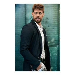 Man wearing a dark blazer and white shirt standing against a teal textured background in a portrait photograph by Jeff Lipsky.