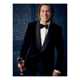 Brad Pitt in a black velvet tuxedo holding an Oscar statuette against a blue patterned wallpaper background