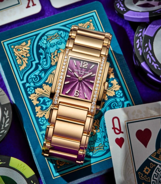 Elegant gold wristwatch with diamond accents on a blue surface with playing cards and poker chips, creating a luxurious casino vibe.