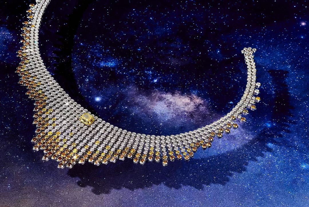 Elegant diamond necklace with yellow and brown stones set against a cosmic starscape background, creating a luxurious celestial jewelry piece.