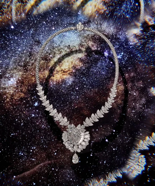 Diamond necklace with a pear-shaped pendant, against a dark cosmic background with white and blue star-like clusters, opulent jewellery.