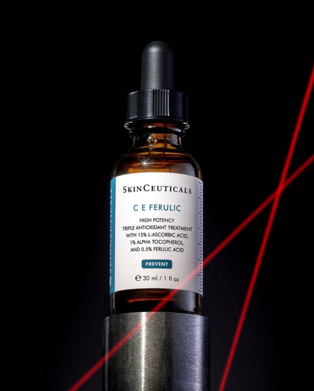 Skinceuticals C E Ferulic antioxidant treatment in amber glass bottle on a metal stand against a dark background with red laser lines.