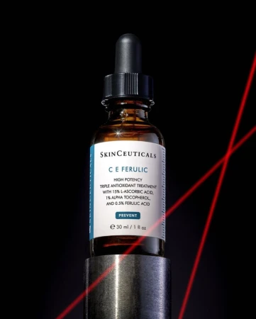 Skinceuticals C E Ferulic antioxidant treatment in amber glass bottle on a metal stand against a dark background with red laser lines.