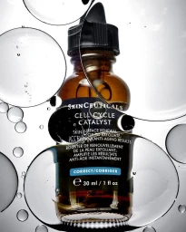 Skinceuticals Cell Cycle Catalyst serum bottle viewed through large translucent water droplets on a pale background