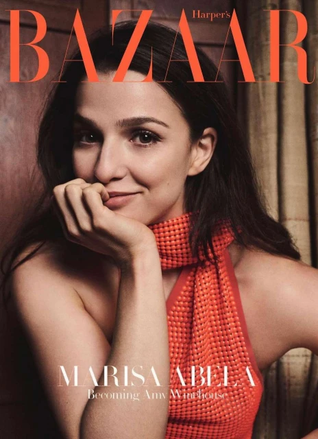 Marisa Abela gazes with a slight smile on Harper's Bazaar cover, sporting an orange textured top, dark hair, and soft, diffused lighting.