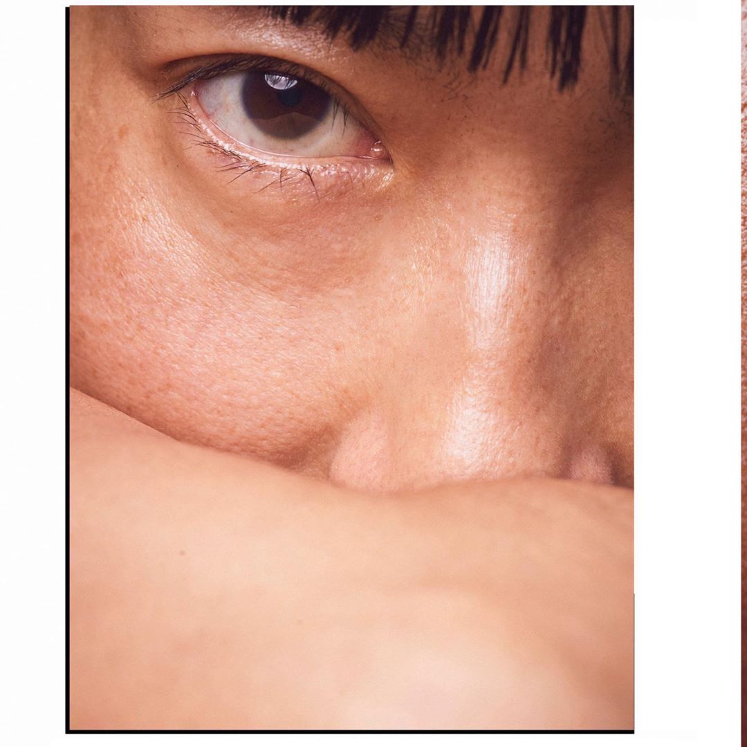 Close-up portrait of an Asian adult woman's face, featuring her eye and cheek; a study in skin texture, makeup, and natural beauty.