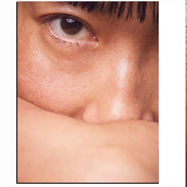 Close-up portrait of an Asian adult woman's face, featuring her eye and cheek; a study in skin texture, makeup, and natural beauty.