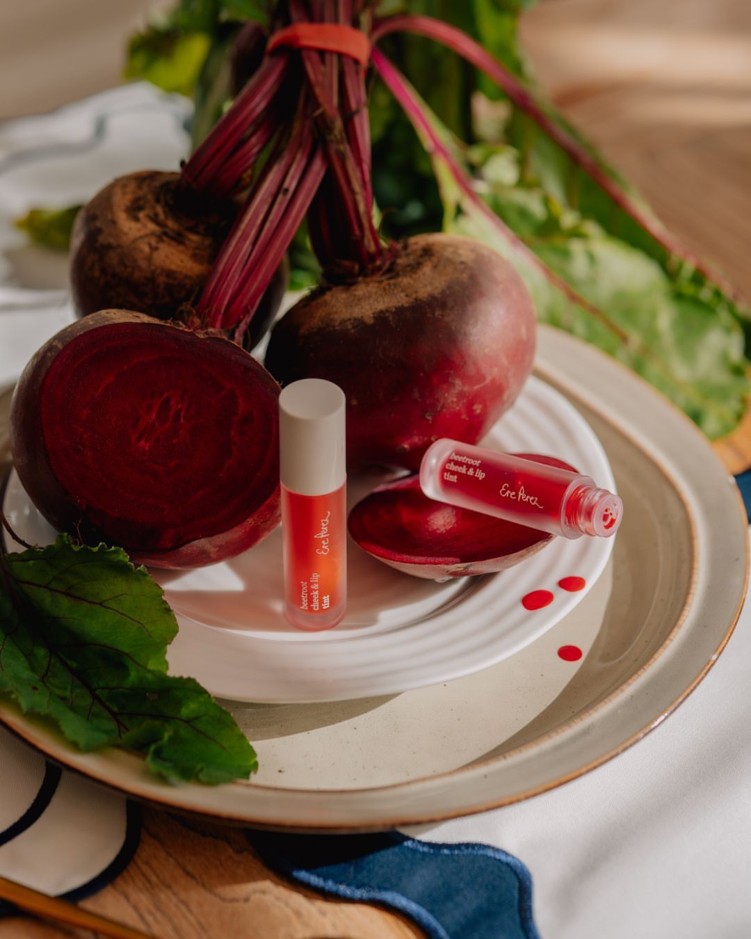 Still life of beetroot and vegan lip tint product on a plate. Natural beauty product against a backdrop of fresh, raw beets.