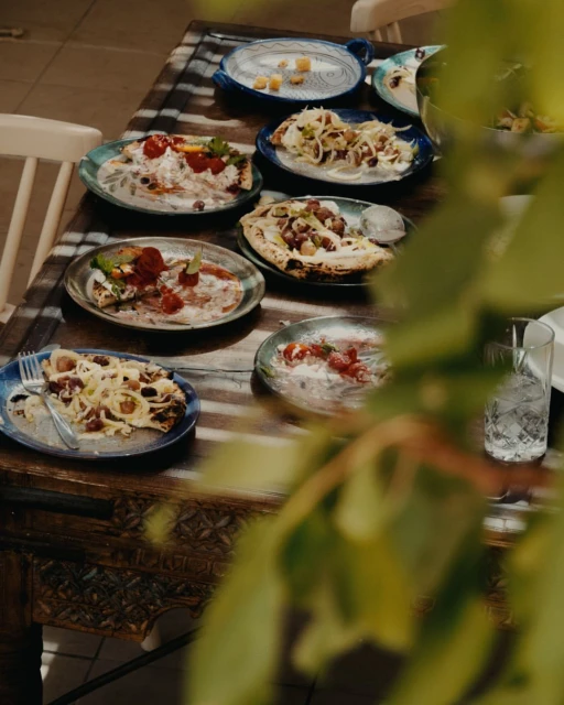 Overhead view of an outdoor table with plates of diverse food, reflecting the culinary arts, and captured in warm, inviting tones.