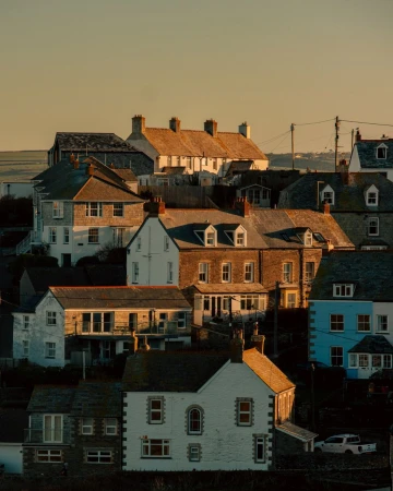 Residential neighbourhood in Cornwall, England with houses of varying heights and colors, captured during a sunny, golden hour.