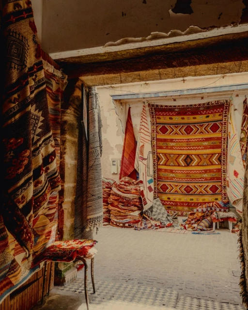 Display of various colorful rugs and textiles hanging in an indoor market, showcasing a variety of patterns and textures.