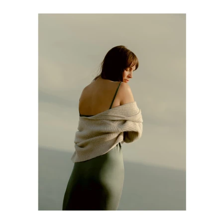 Woman in a green slip dress and cream knit cardigan posed against an overcast sky by photographer Jenna Foxton