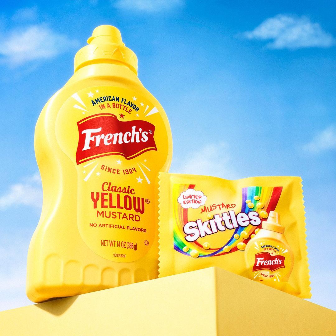 French's mustard bottle and Skittles candy in a promotional still life against a bright blue sky. The yellow hues dominate the shot.