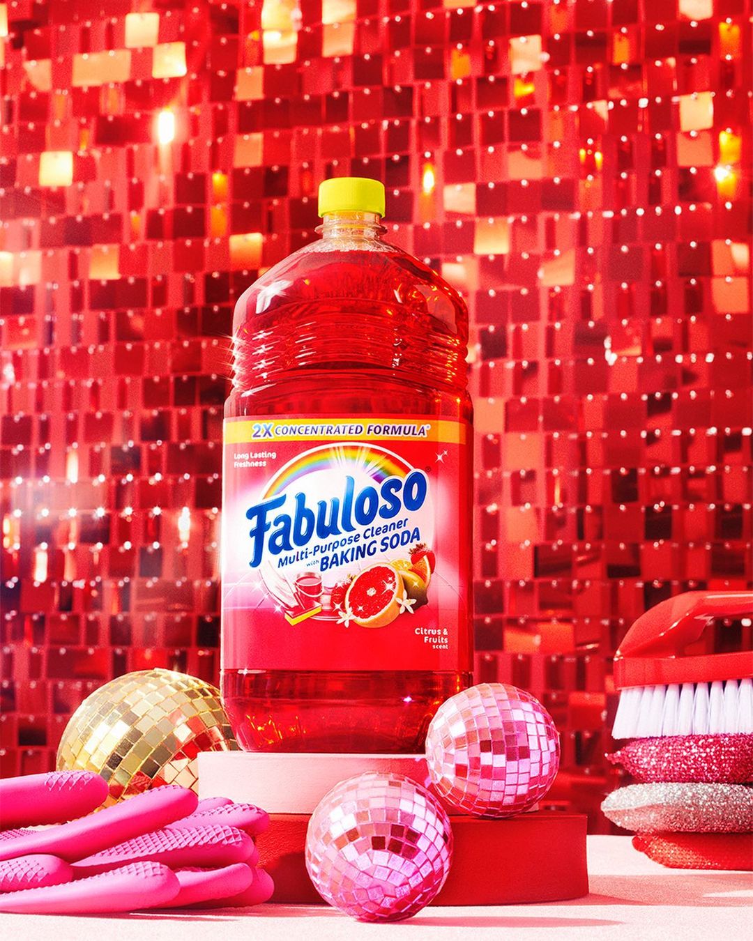 Bottle of Fabuloso multi-purpose cleaner with disco balls and cleaning brush against a shiny red sequin backdrop.