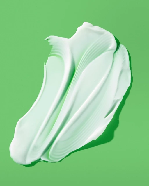 Close-up of a light green cosmetic cream smear on a pastel green background. Perfect for beauty, skincare, or product photography concepts.