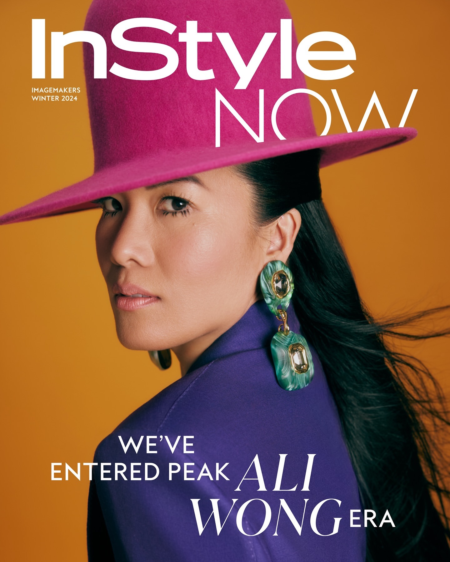 Magazine cover featuring a portrait of a woman with dark hair wearing a pink hat and statement earrings against an orange background.