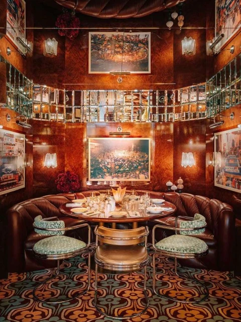 Luxurious dining room booth in warm, inviting lighting, featuring a table set for a meal with a plush banquette and stylish chairs.
