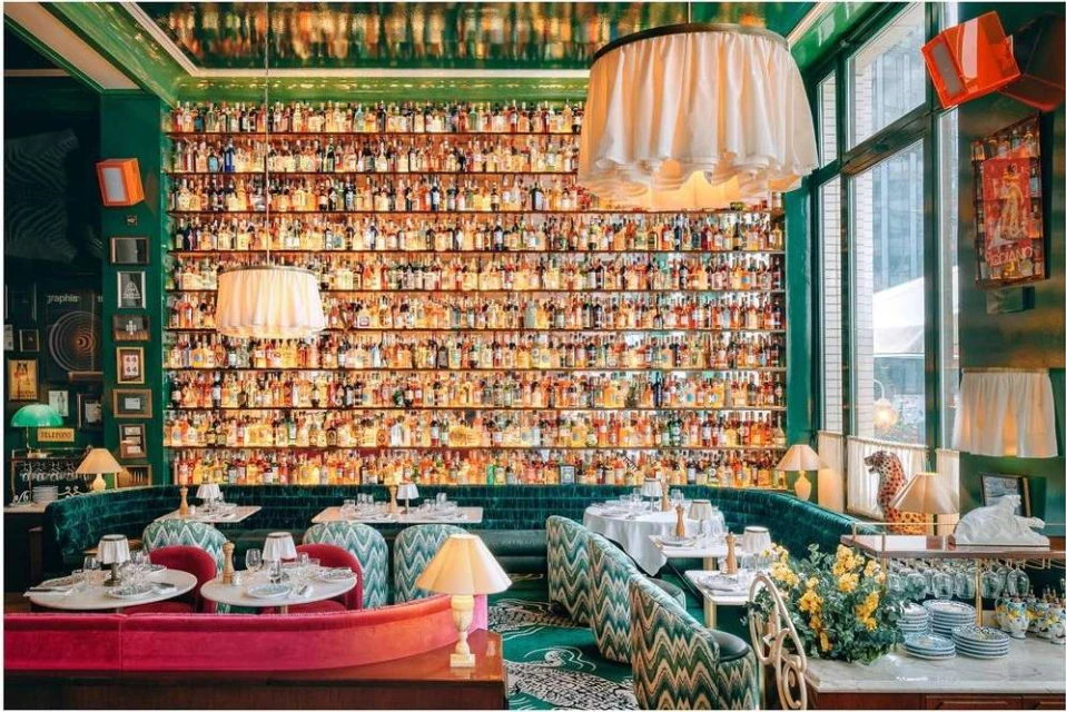 Opulent restaurant interior showcases a vast wall display of liquor bottles, elegant tables, and luxurious seating arrangements, creating a sophisticated ambiance.