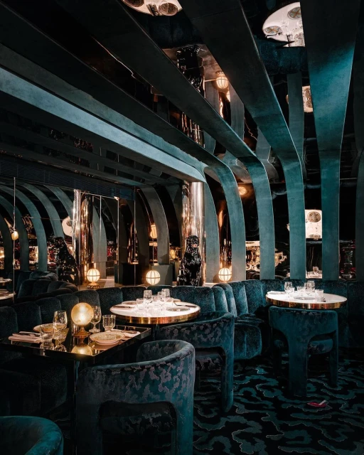 Opulent restaurant interior with velvet seating, golden accents, globe lights, creating a luxurious, art deco-inspired dining ambiance.