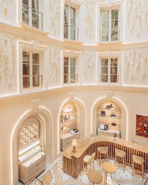 Interior of a boutique store with an ornate arched display, counters, and seating, illuminated by recessed lighting in a multi-story space.