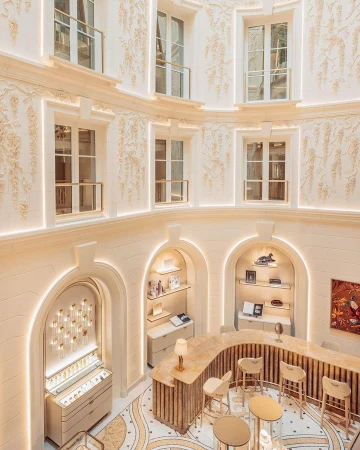 Interior of a boutique store with an ornate arched display, counters, and seating, illuminated by recessed lighting in a multi-story space.