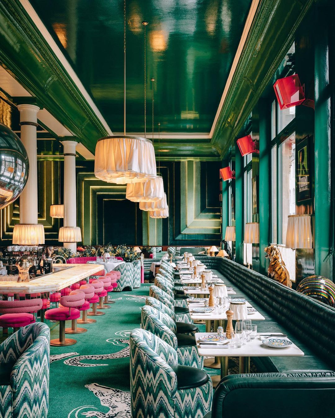 Elegant restaurant interior with patterned carpet and chairs, tables set for dining, and decorative light fixtures and interior design.