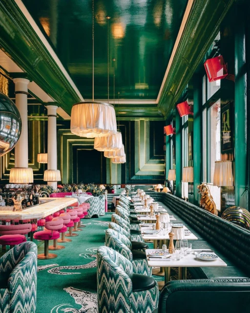 Elegant restaurant interior with patterned carpet and chairs, tables set for dining, and decorative light fixtures and interior design.