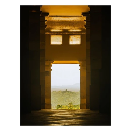 View through architectural columns of Borobudur temple in distance, Java, Indonesia. Sunlight highlights the columns and distant landscape.
