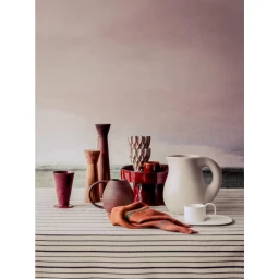 Still life tabletop with ceramic vessels, wooden grinders, and a textile cloth against a muted painted wall by Jerome Galland.