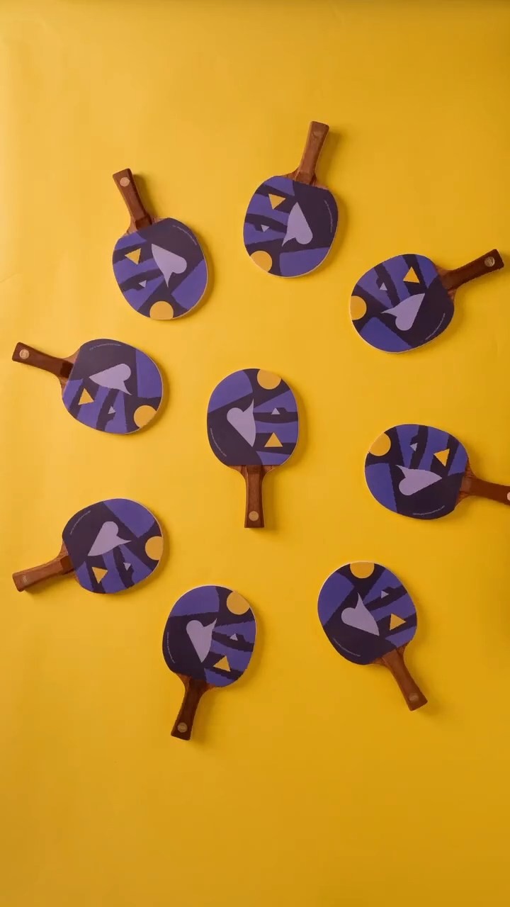 Group of table tennis paddles arranged on a bright yellow background, creating a playful and eye-catching visual composition.