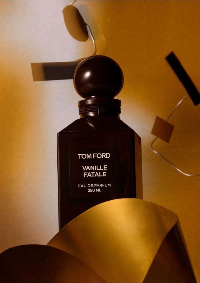 Tom Ford Vanille Fatale perfume bottle in a studio setting with warm lighting and golden ribbon accents, luxury beauty product.