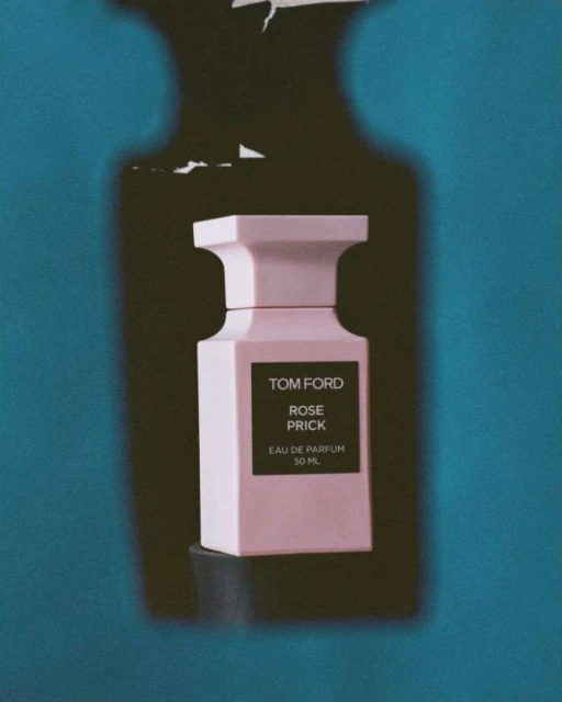 Pink Tom Ford Rose Prick perfume bottle with the product name displayed on the black label against a blue backdrop.