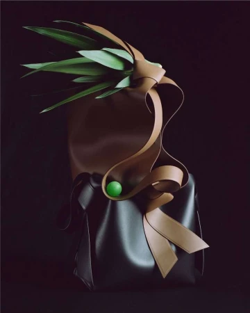 An artistic still life featuring a brown leather tote bag decorated with green leaves and a tan leather ribbon, against a dark background.