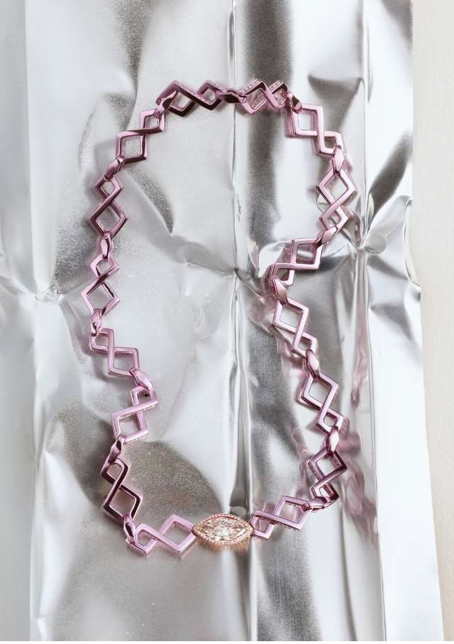 Geometric pink necklace with diamond accent on shimmering silver backdrop. Fashion accessory still life, studio lighting, close-up product shot.