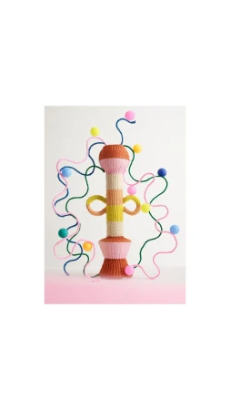 Handcrafted art piece featuring yarn and pom poms in pastel colors, against a white backdrop, evoking a playful and whimsical aesthetic.