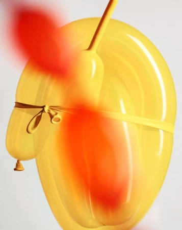 Close-up of a yellow and red balloon animal tied with a yellow rubber band against a plain background, showcasing its shape and texture.