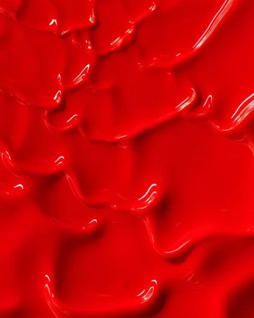 Bright red glossy paint, creating a striking, abstract, textural background; perfect for adding bold color and tactile depth to visuals.