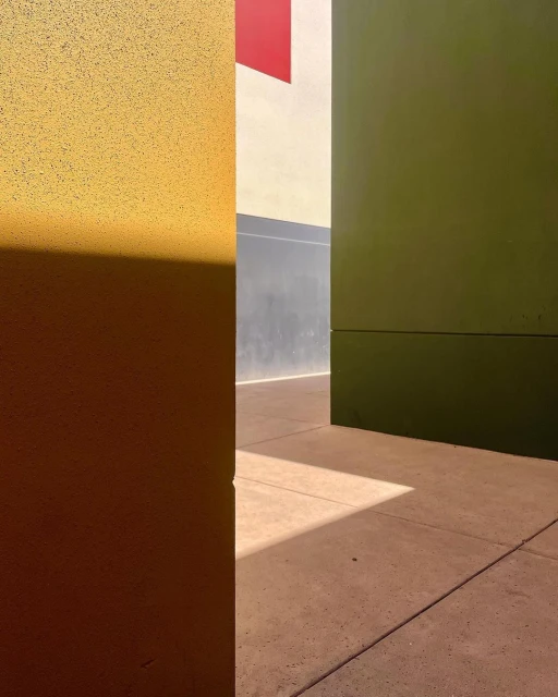 Abstract architecture featuring geometric shapes, colorful walls in shades of yellow, green, red, and gray, and natural light and shadow play.
