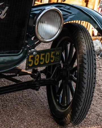 Close-up of a vintage green Ford vehicle showcasing the headlight, tire, and 1919 license plate with the number 58505.