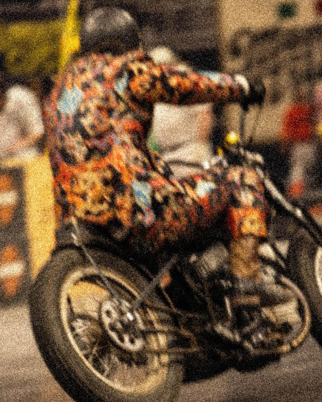 Motorcyclist wearing colorful racing suit and helmet on a motorbike, racing in an outdoor event, action shot.