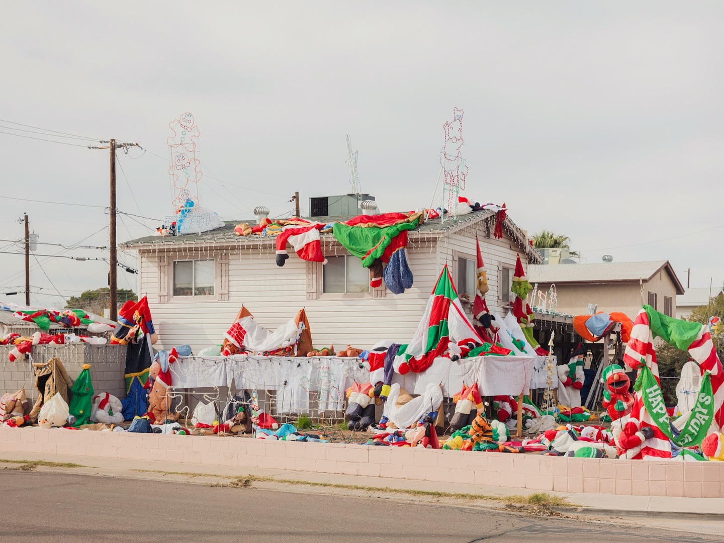 Extravagant Christmas display on a residential house, featuring numerous inflatable holiday decorations, lights, and festive adornments.