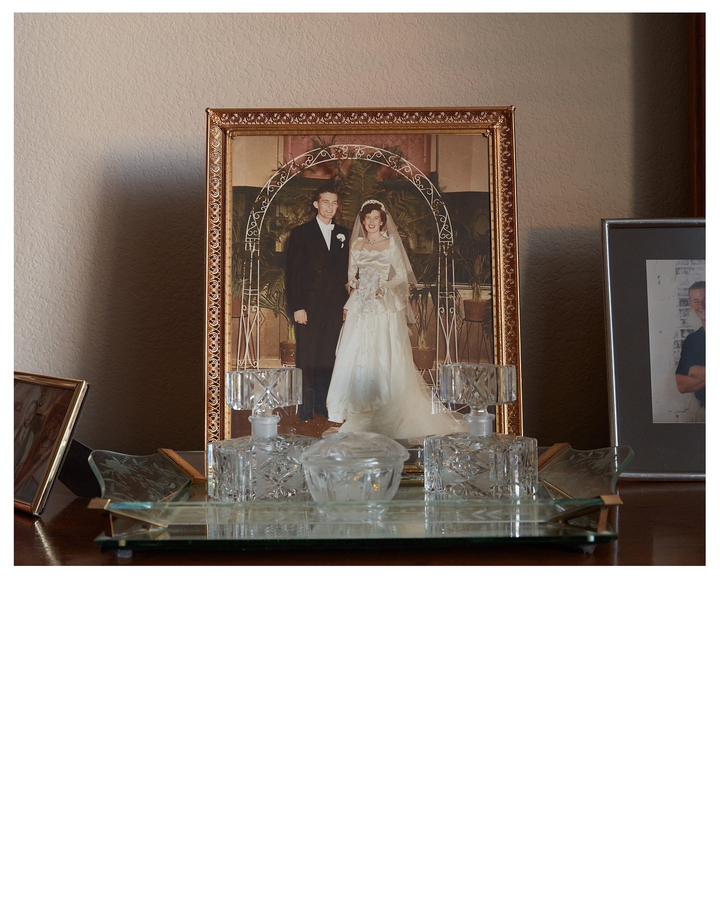 Framed wedding photo with a man and woman in a white dress, displayed on a wooden surface with decorative glass bottles and containers.